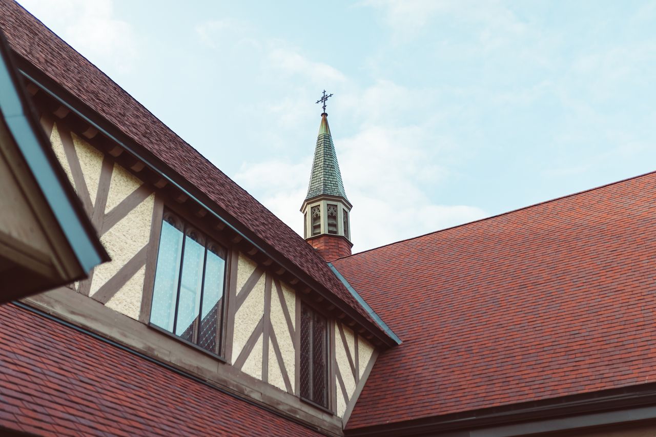 Close-up view of a church steeple with timbered architecture against a clear sky.